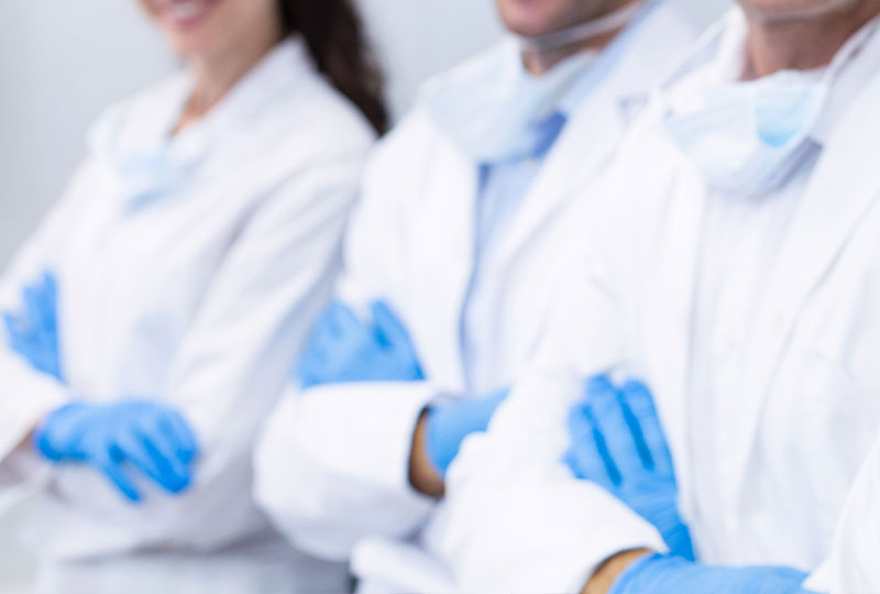 A group of five individuals, possibly dental professionals, in a dental office setting, celebrating with raised hands and thumbs up.
